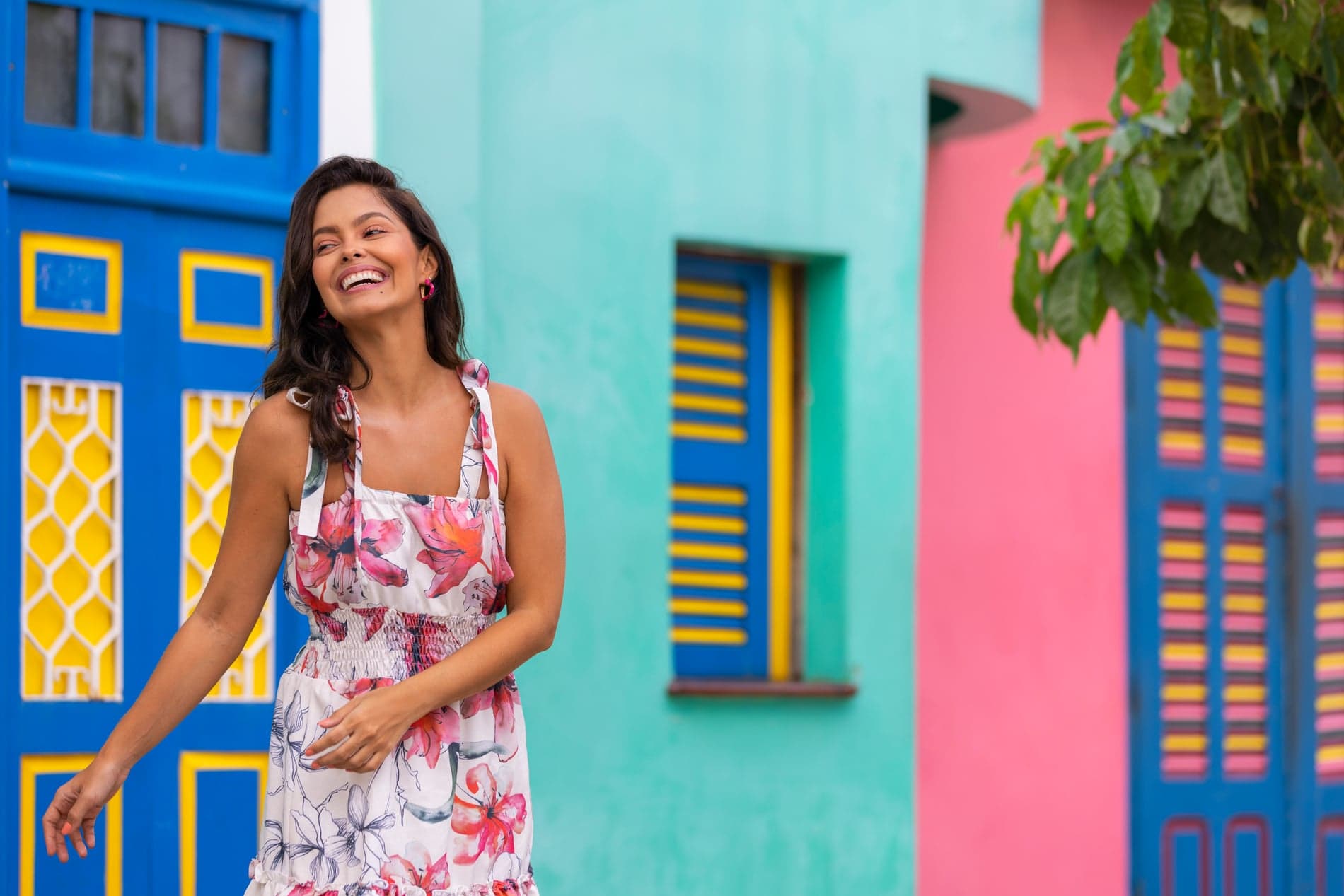 Mujer sonriendo frente a las casas de colores de un pueblo dominicano
